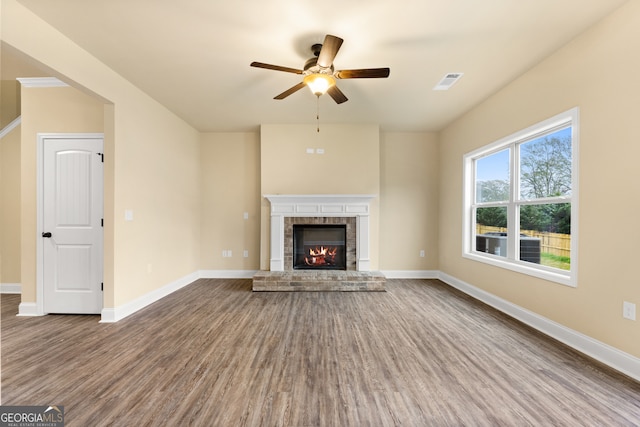 unfurnished living room featuring a fireplace, wood-type flooring, and ceiling fan