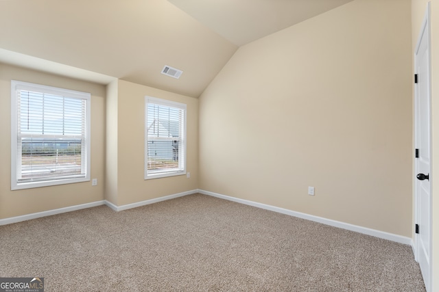 empty room with light colored carpet, plenty of natural light, and vaulted ceiling