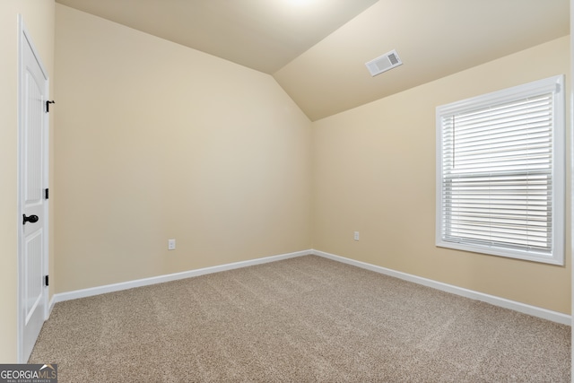 carpeted empty room with lofted ceiling