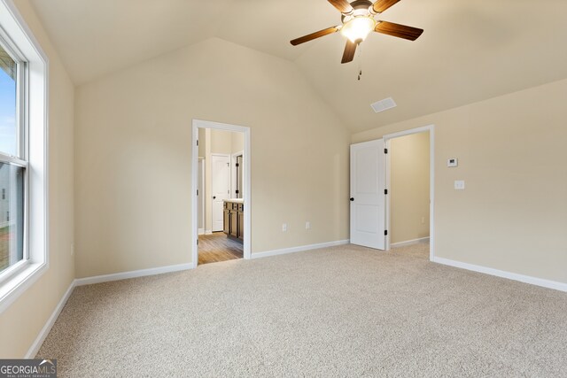 unfurnished bedroom with lofted ceiling, ceiling fan, light carpet, and ensuite bathroom