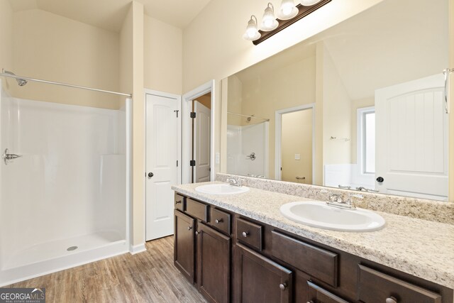 bathroom with vanity, hardwood / wood-style floors, walk in shower, and lofted ceiling