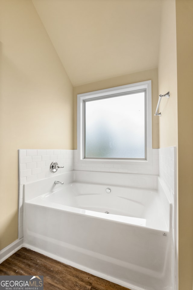 bathroom with a wealth of natural light, hardwood / wood-style floors, and a bathtub