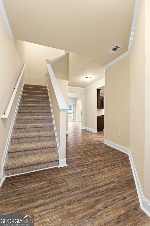 stairway featuring crown molding and hardwood / wood-style floors