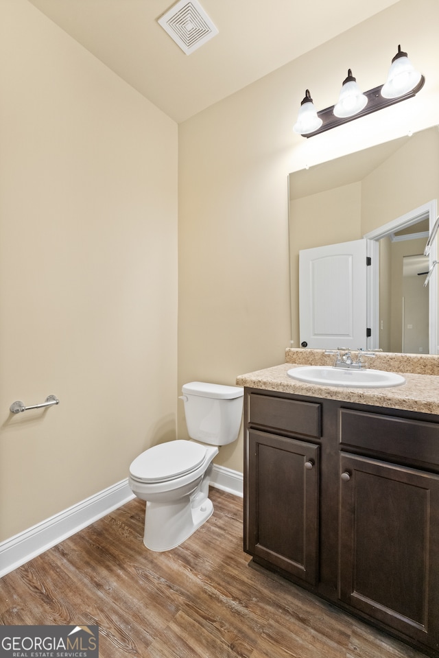 bathroom featuring toilet, hardwood / wood-style flooring, and vanity