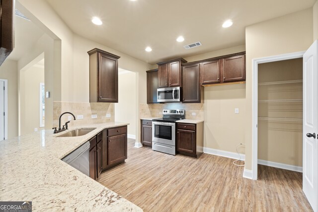 kitchen featuring light stone counters, sink, appliances with stainless steel finishes, and decorative backsplash