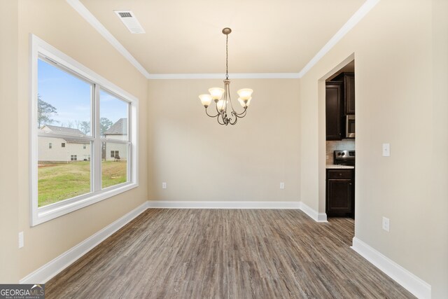 unfurnished dining area featuring ornamental molding, wood-type flooring, and a chandelier