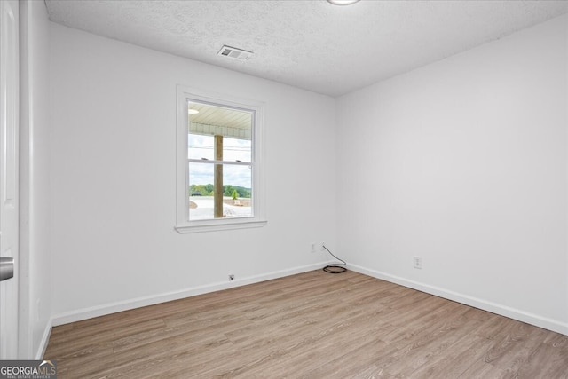 unfurnished room with a textured ceiling and light hardwood / wood-style flooring