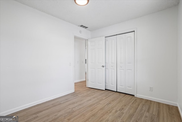 unfurnished bedroom with light wood-type flooring and a closet