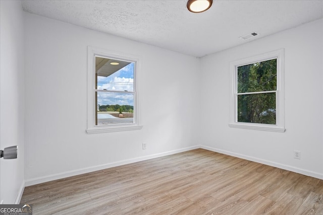 spare room with light wood-type flooring and a textured ceiling