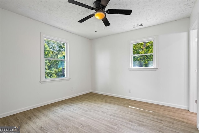 unfurnished room featuring ceiling fan, light hardwood / wood-style floors, a textured ceiling, and a healthy amount of sunlight