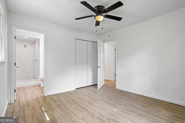 unfurnished bedroom with a textured ceiling, light hardwood / wood-style flooring, connected bathroom, ceiling fan, and a closet