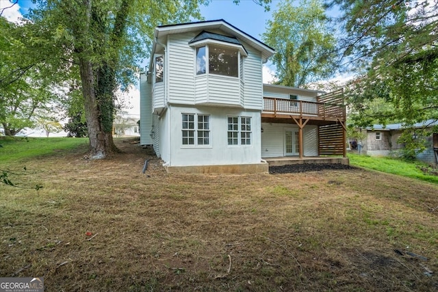 rear view of house featuring a lawn and a deck