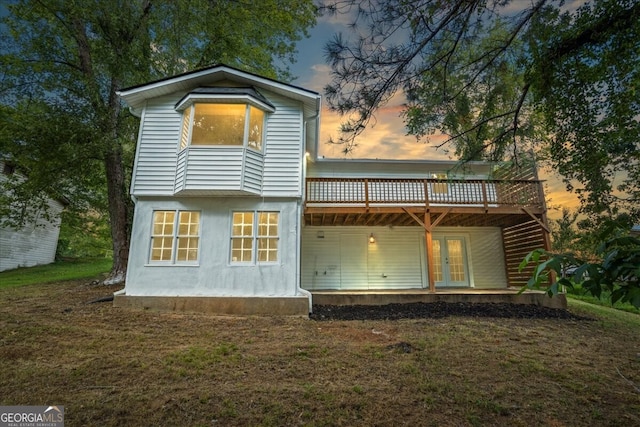 back house at dusk featuring a yard, french doors, and a deck