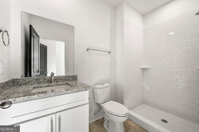 bathroom featuring a tile shower, vanity, toilet, and tile patterned floors