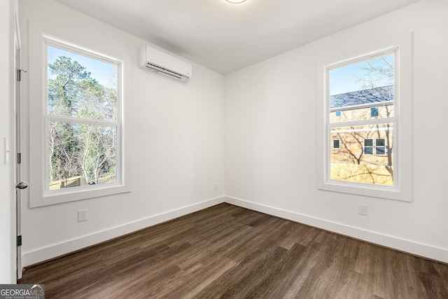 spare room with a wall mounted air conditioner, dark wood-type flooring, and a healthy amount of sunlight