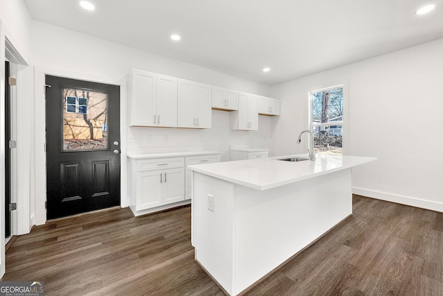 kitchen featuring dark hardwood / wood-style flooring, white cabinetry, sink, and a kitchen island with sink