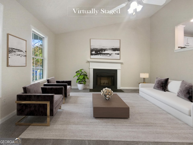 carpeted living room with lofted ceiling, a fireplace with flush hearth, baseboards, and a ceiling fan