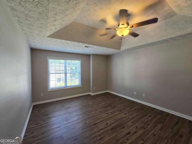 spare room with a textured ceiling, ceiling fan, and dark hardwood / wood-style flooring