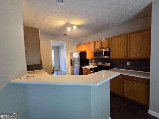 kitchen with appliances with stainless steel finishes, sink, kitchen peninsula, decorative backsplash, and a textured ceiling