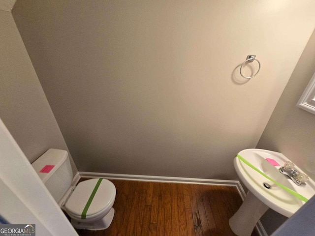 bathroom with toilet, sink, and hardwood / wood-style flooring