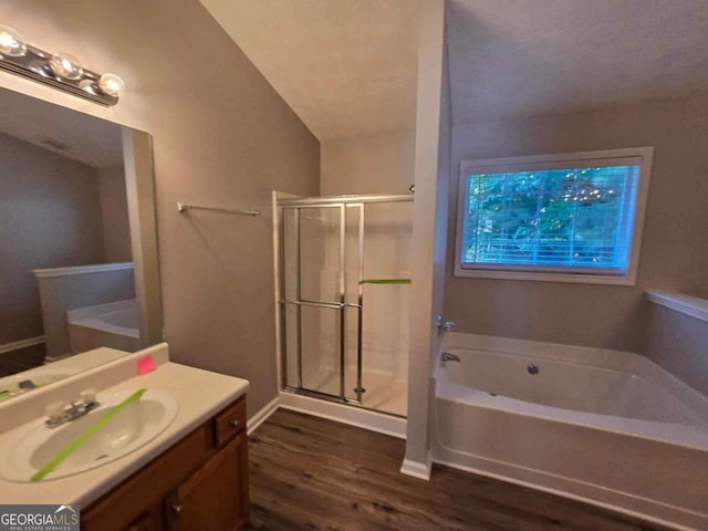 bathroom featuring vanity, vaulted ceiling, hardwood / wood-style flooring, and shower with separate bathtub