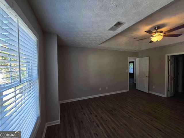 unfurnished room with a textured ceiling, ceiling fan, and dark hardwood / wood-style flooring