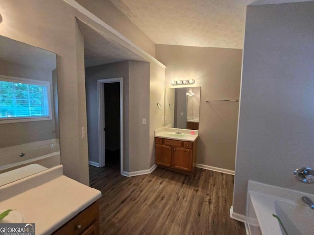 bathroom featuring hardwood / wood-style floors, a washtub, a textured ceiling, and vanity