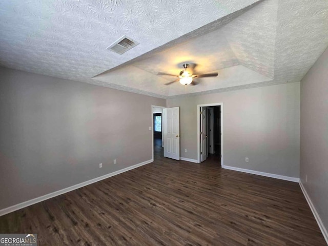 unfurnished bedroom with a tray ceiling, dark hardwood / wood-style flooring, ceiling fan, and a textured ceiling