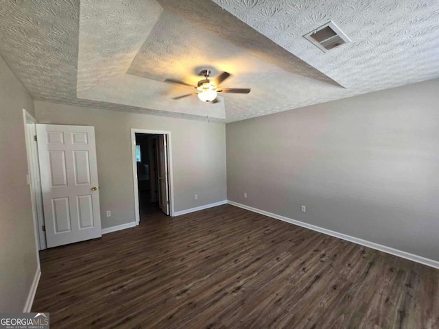 unfurnished bedroom with ceiling fan, dark hardwood / wood-style floors, a raised ceiling, and a textured ceiling