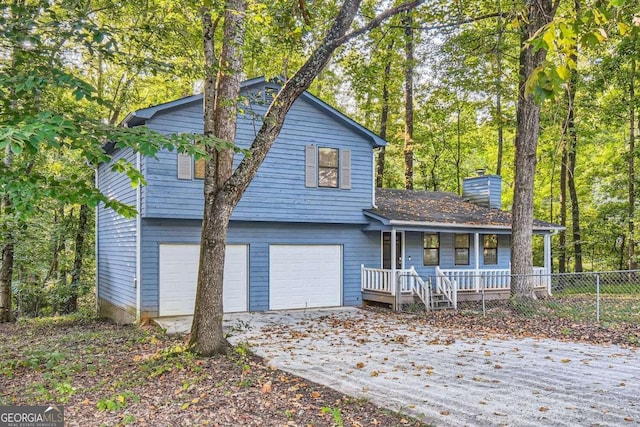 view of front facade with an attached garage, fence, a porch, a chimney, and driveway