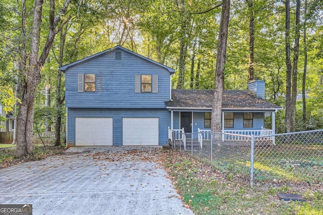 split level home with a fenced front yard, driveway, a chimney, and a garage