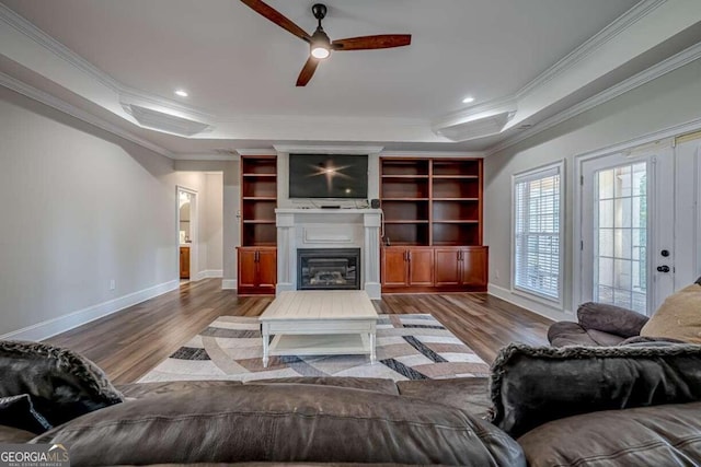 living room with ceiling fan, hardwood / wood-style flooring, a raised ceiling, and ornamental molding