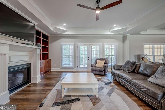 living room with dark wood-type flooring, ceiling fan, a wealth of natural light, and crown molding