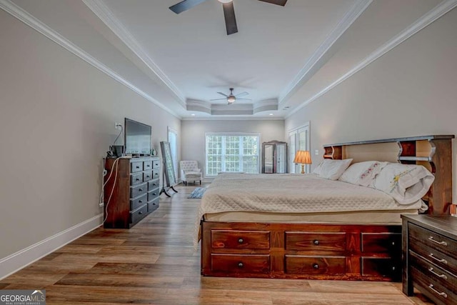 bedroom featuring hardwood / wood-style flooring, a raised ceiling, and crown molding