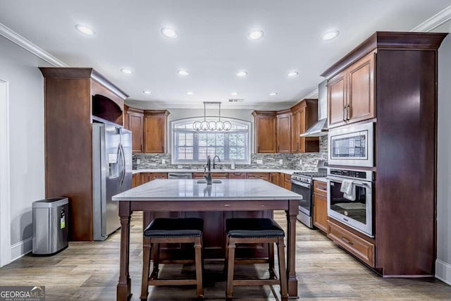 kitchen with crown molding, light hardwood / wood-style flooring, decorative light fixtures, stainless steel appliances, and a kitchen island