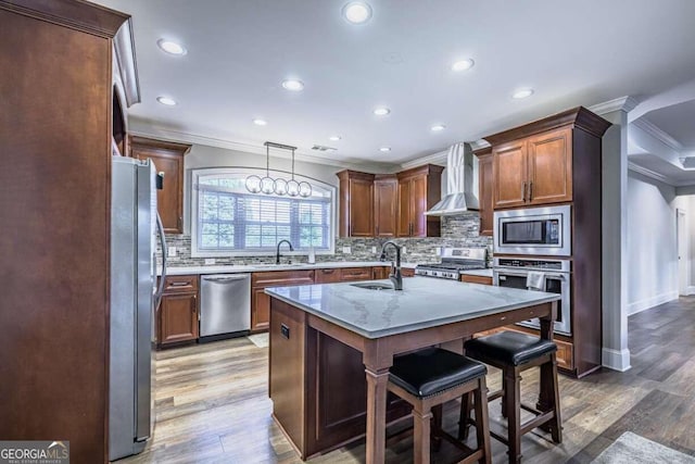 kitchen featuring wall chimney exhaust hood, appliances with stainless steel finishes, crown molding, sink, and hardwood / wood-style flooring