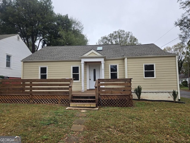 bungalow with a front yard and a wooden deck