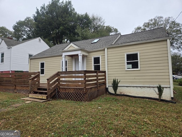 rear view of house with a lawn and a wooden deck