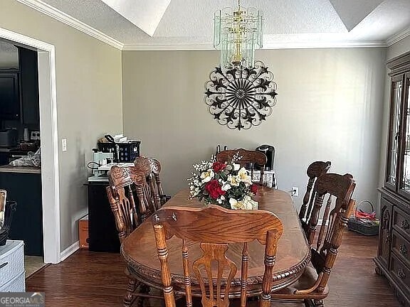 dining room with ornamental molding, dark hardwood / wood-style flooring, a chandelier, and a textured ceiling