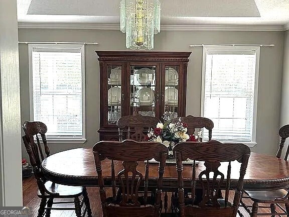 dining space with ornamental molding, plenty of natural light, and a notable chandelier