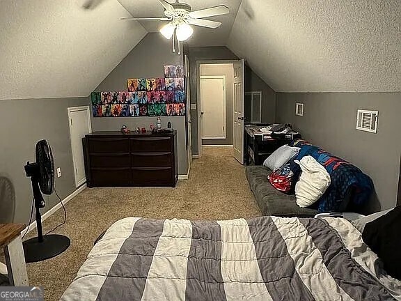 bedroom featuring a textured ceiling, light colored carpet, ceiling fan, and vaulted ceiling