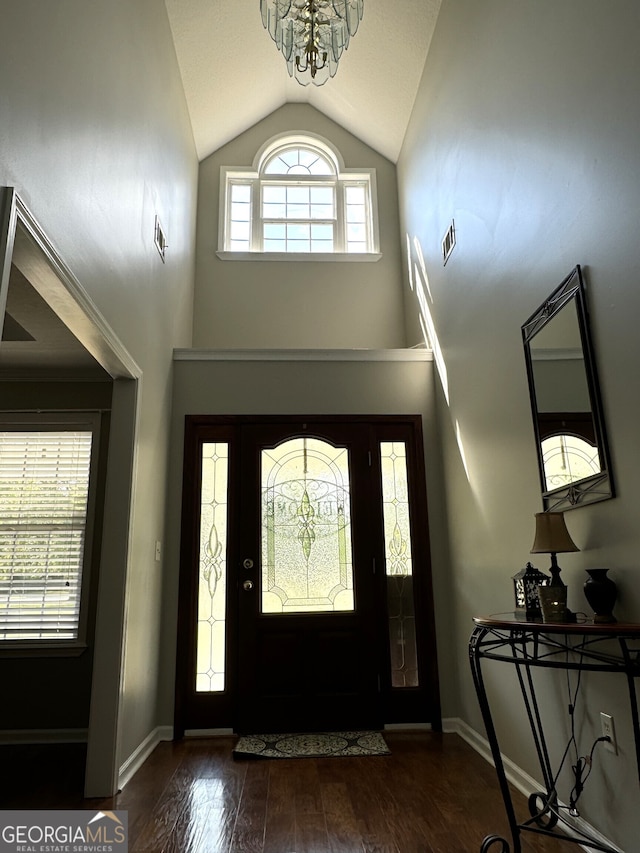 entrance foyer with vaulted ceiling, dark hardwood / wood-style flooring, and a notable chandelier