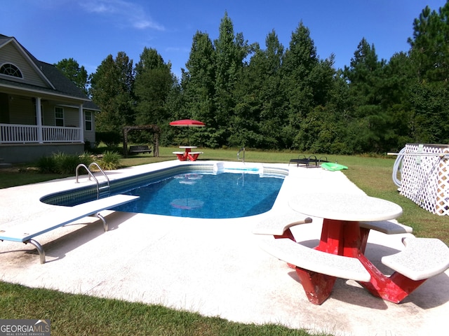 view of pool featuring a lawn, a diving board, and a patio