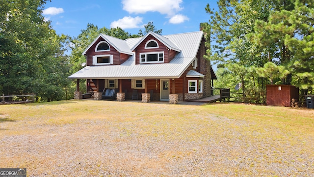 view of front of property with a storage unit, covered porch, and a front yard