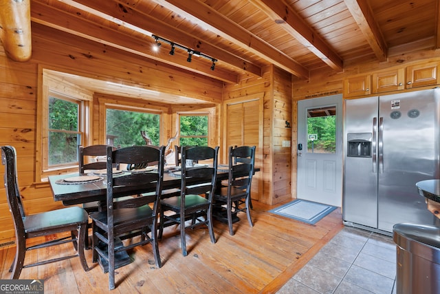 dining space with light wood-type flooring, wood walls, wood ceiling, and beamed ceiling