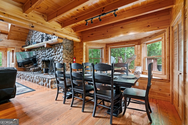 dining space with wood walls, plenty of natural light, and light hardwood / wood-style flooring