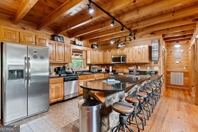 kitchen featuring a kitchen bar, wood ceiling, appliances with stainless steel finishes, and light hardwood / wood-style floors