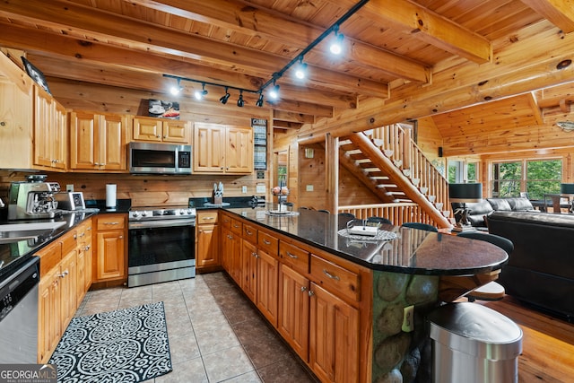 kitchen with wood ceiling, stainless steel appliances, beamed ceiling, and dark stone counters