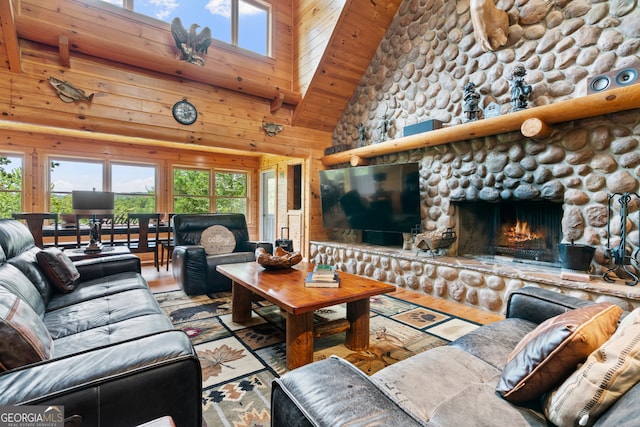 living room featuring high vaulted ceiling, plenty of natural light, light hardwood / wood-style flooring, and a stone fireplace