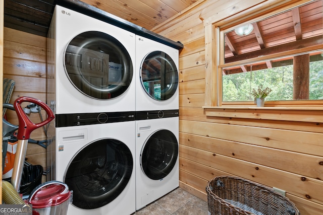 laundry room with wooden ceiling, light tile patterned flooring, wood walls, and stacked washer and dryer